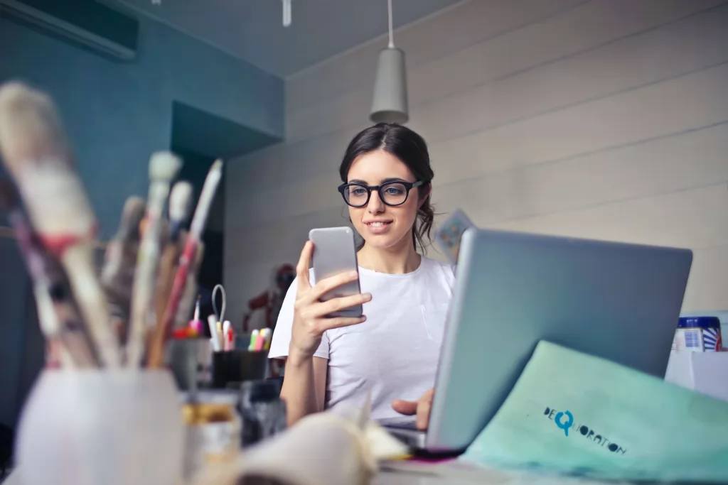kobieta przy biurku z laptopem i telefonem w ręce - jak założyć firmę w niemczech