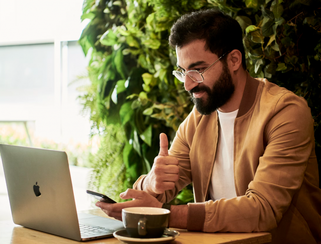 Mężczyzna w brązowej kurtce siedzący przy stole i patrzący na laptopa. - Strategie marketingowe dla Gewerbe